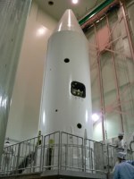 The nose fairing is a white cylinder with conical top.  There are still a few small holes visible, for access to the spacecraft.  They will be sealed later.