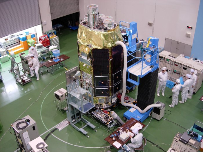 Astro-E2 stands in the clean room, surrounded by wires, gas bottles, electronics, technicians, engineers, and scientists. (102K JPEG)