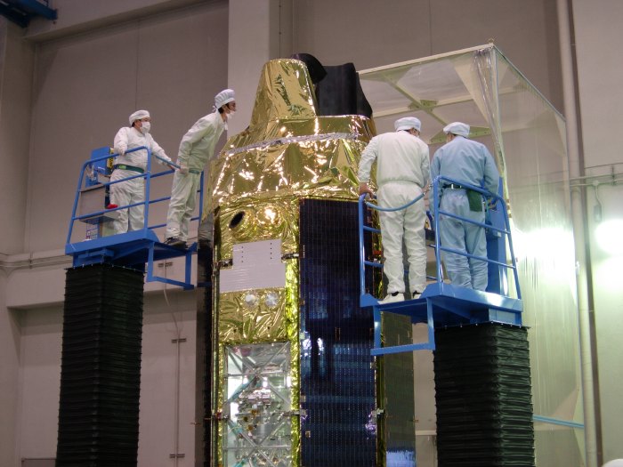 Two pairs of ISAS engineers, clad in stunning white cleanroom suits, peer carefully over the top of the spacecraft from their locations atop a pair of hydraulic lifts. (77K JPEG)