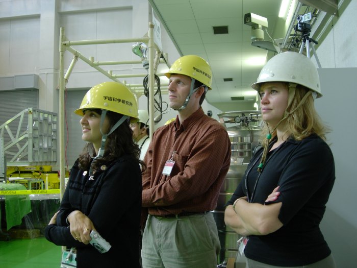 Three NASA engineers look intently off-screen stage right, yellow ISAS hardhats perched jauntily atop their heads. (72K JPEG)
