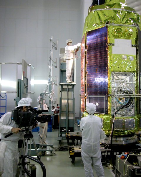 Bright lights shine on the checkerboard of solar cells on the side of a spacecraft. (76K JPEG)