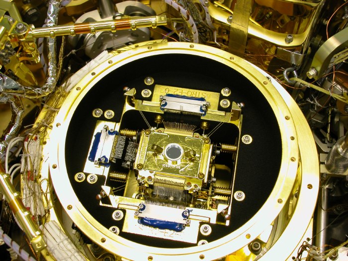 The gold-plated FEA innards seem to float in the black circle of the outer FEA cylinder (because the inner sides of that cylinder are painted black).  A mass of wires and tubes surrounds the tableau. (133K JPEG)